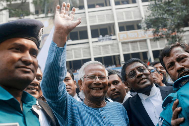 Muhammad Yunus waves to supporters outside